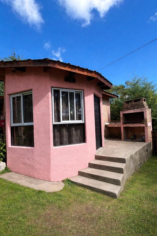 a small pink house with stairs in the grass at CABAÑAS SANTA RITA - Tanti, Córdoba in Tanti
