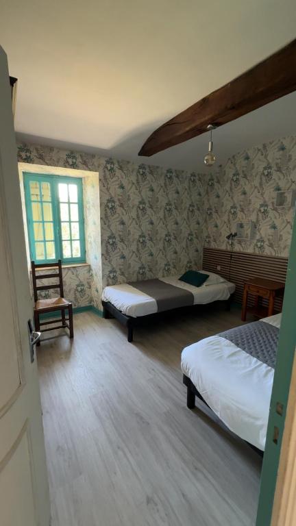 a bedroom with two beds and a chair and a window at Maison avec Jacuzzi extérieur in Le Fief-Sauvin