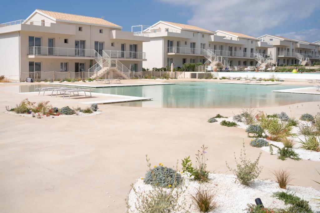 a swimming pool in front of some apartment buildings at GuestHost - Borgo 84 Marzamemi - Terrazza Mare in Marzamemi