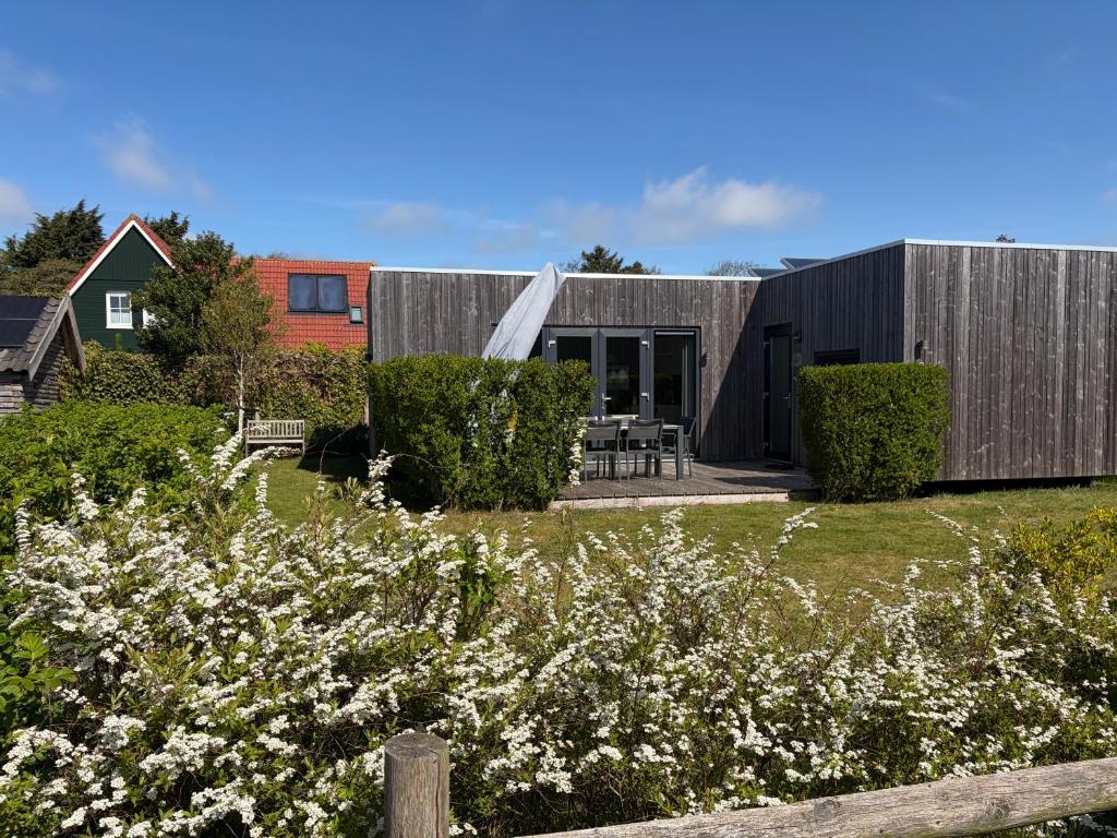 a wooden house with a garden in front of it at Anpektop - Ecohuisjes Terschelling in Midsland