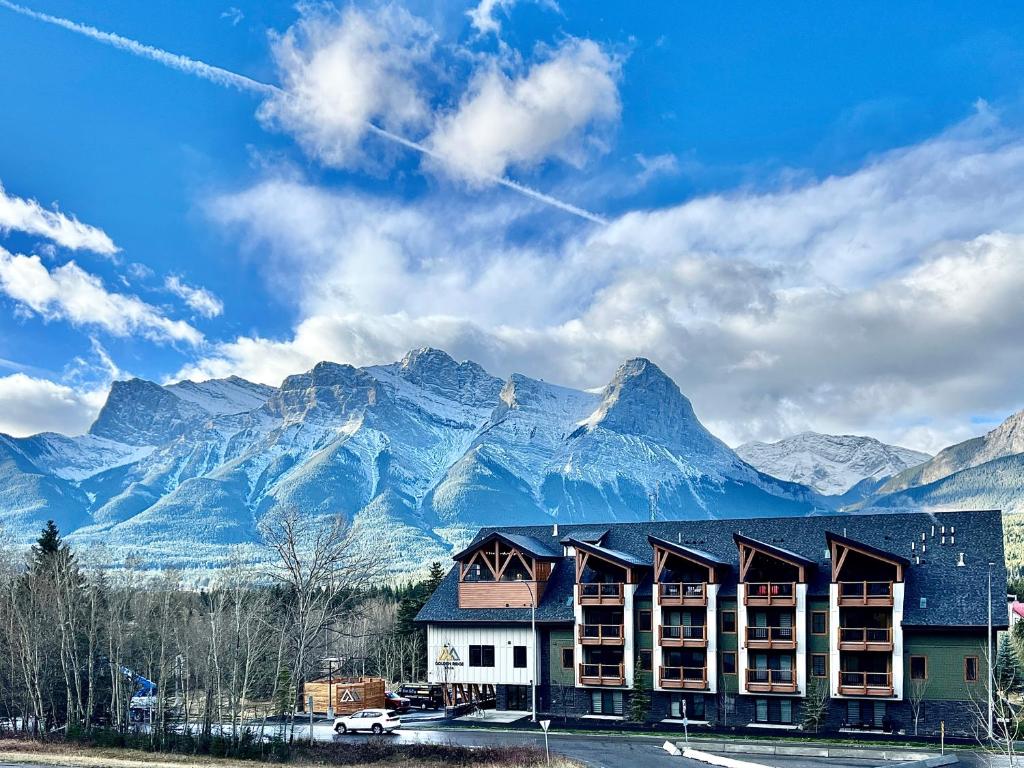 a building in front of a mountain with mountains at Golden Ridge Collection in Canmore