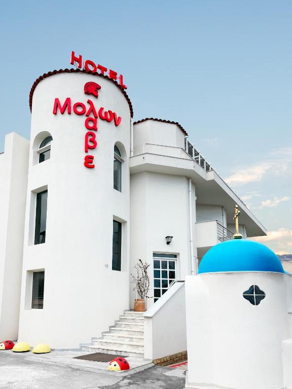 a white building with a neon sign on it at Molon Lave in Nea Roda