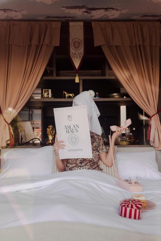 a woman laying on a bed holding a sign at Aslan Haus in Villarrica
