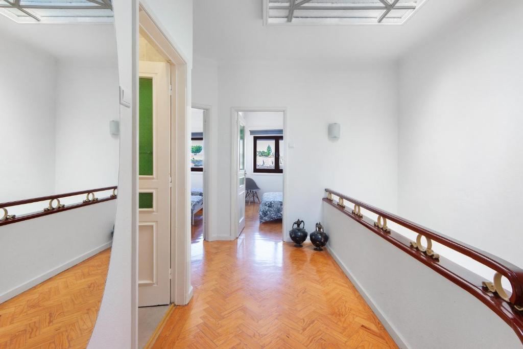 a hallway with white walls and a staircase with wood floors at Azuaga House Sunny Charming Apt in Vila Nova de Gaia