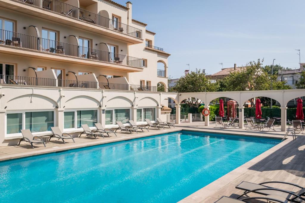 a swimming pool in front of a building at Hotel Canal Olímpic in Castelldefels