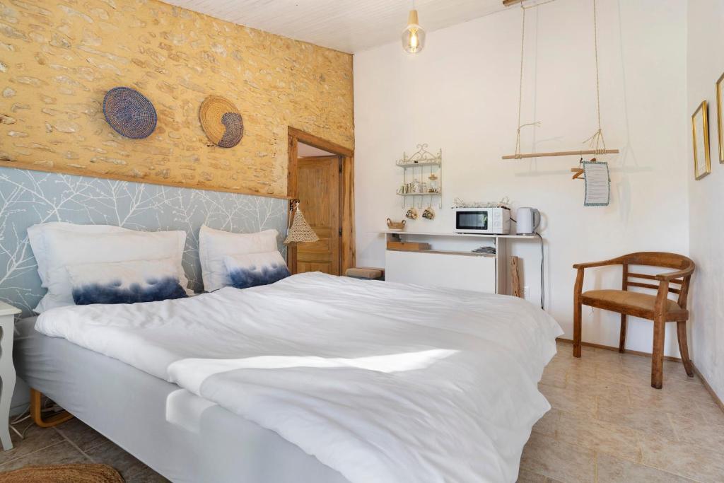 a bedroom with a large white bed and a kitchen at Les Orchidées - Chambre in Savignac-de-Miremont