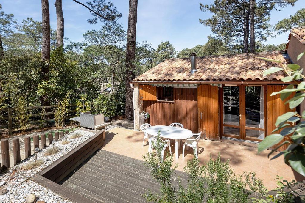 a small wooden cabin with a table and chairs on a patio at Petite Villa Mitoyenne Dans Pinède in Lacanau-Océan