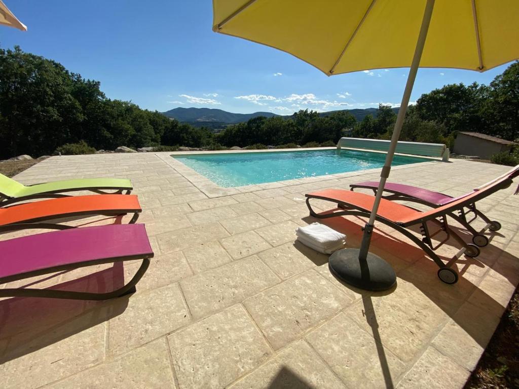 two chairs and an umbrella next to a swimming pool at Villa les Jules in Thoard
