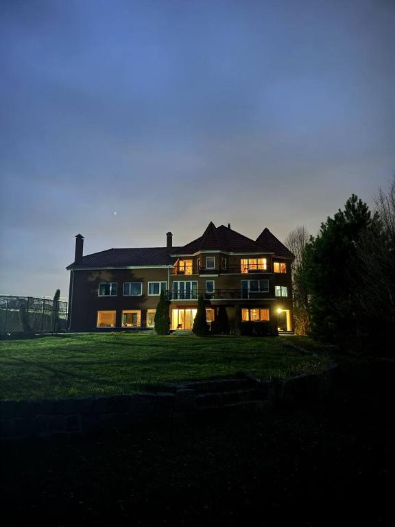 a large house on a grassy field at night at Castle Apartments in Schaslyve