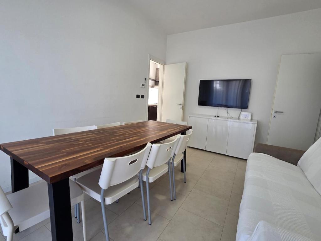 a dining room with a wooden table and white chairs at Appartamenti Federica in Milano Marittima