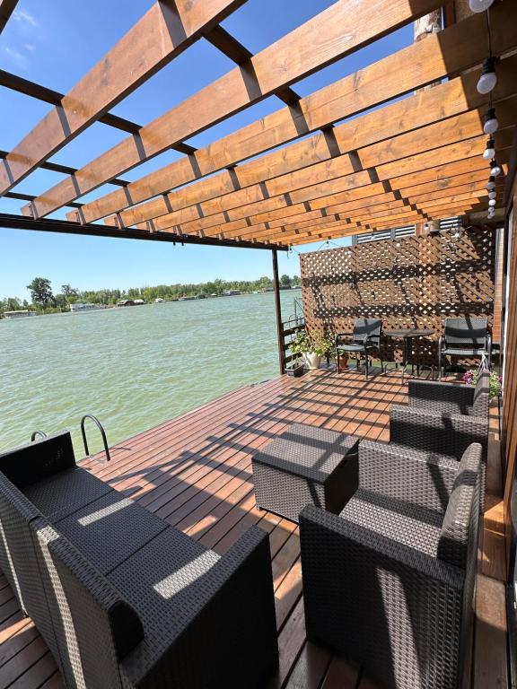 a wooden deck with chairs and tables on the water at Splav Sava in Ostružnica