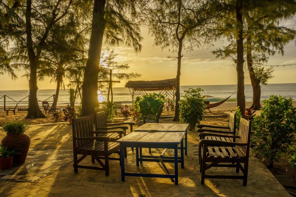 a table and chairs on a beach with the ocean at Tsunami beach hotel arugambay in Pottuvil