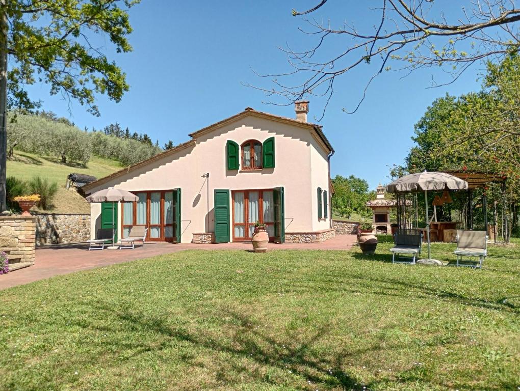 a white house with green doors and a yard at Podere la Campagnola in San Gimignano