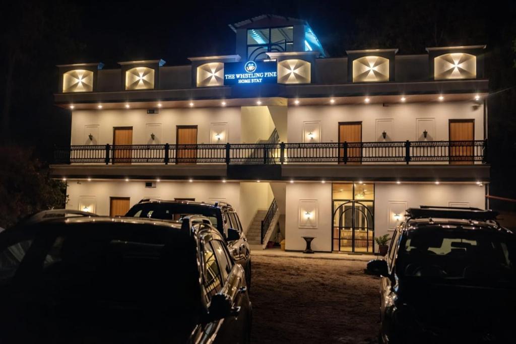 two cars parked in front of a building at night at The Whistling Pine Homestay With Natural Swimming Pool in Lansdowne