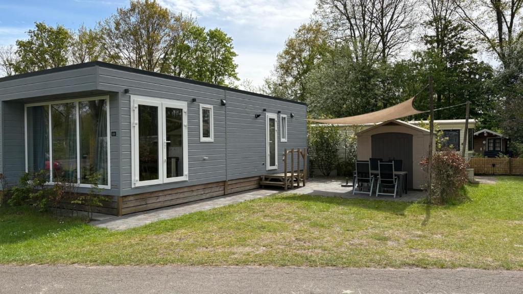 a gray tiny house with a patio in a yard at Chalet Pallegarste 153 in Mariënberg