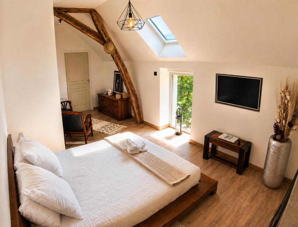 a bedroom with a large white bed and a tv at La Closeraie in Noyers-sur-Cher