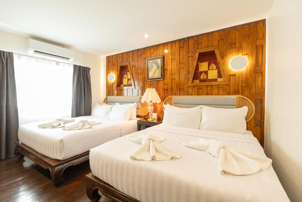 two beds in a hotel room with wooden walls at Hotel Rue De Siam in Chinatown