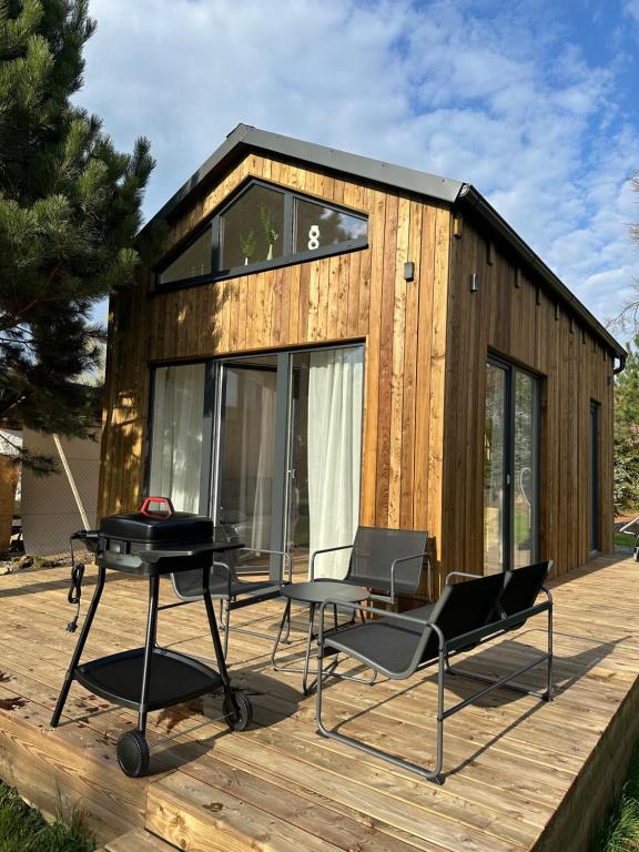 a tiny house with a grill and chairs on a deck at Domeček pod lípou in Neveklov