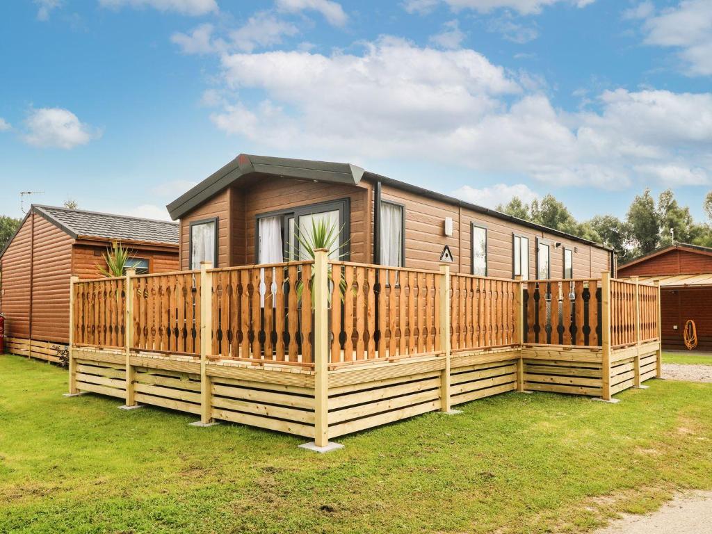 a house with a wooden fence in front of it at Hedgehog Lodge in Carnforth