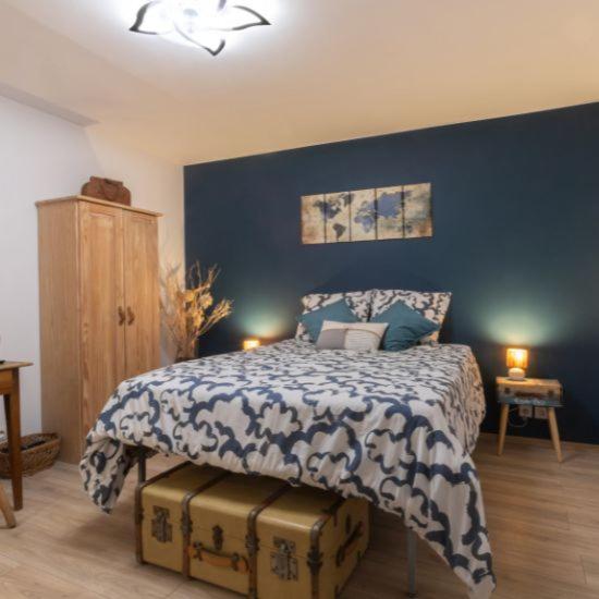 a bedroom with a bed with a blue wall at La Parenthèse in Vitreux