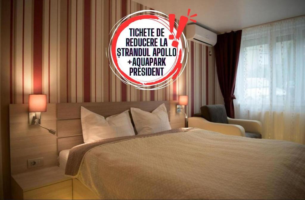 a bedroom with a bed and a sign on the wall at Apartamente Baile Felix in Baile Felix