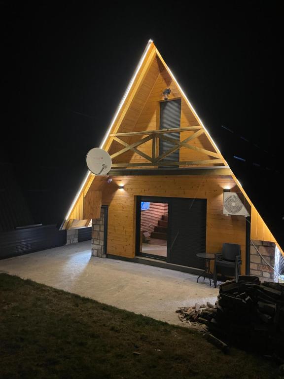 a house with a clock on the roof at night at Black Pine Chalet in Meždo