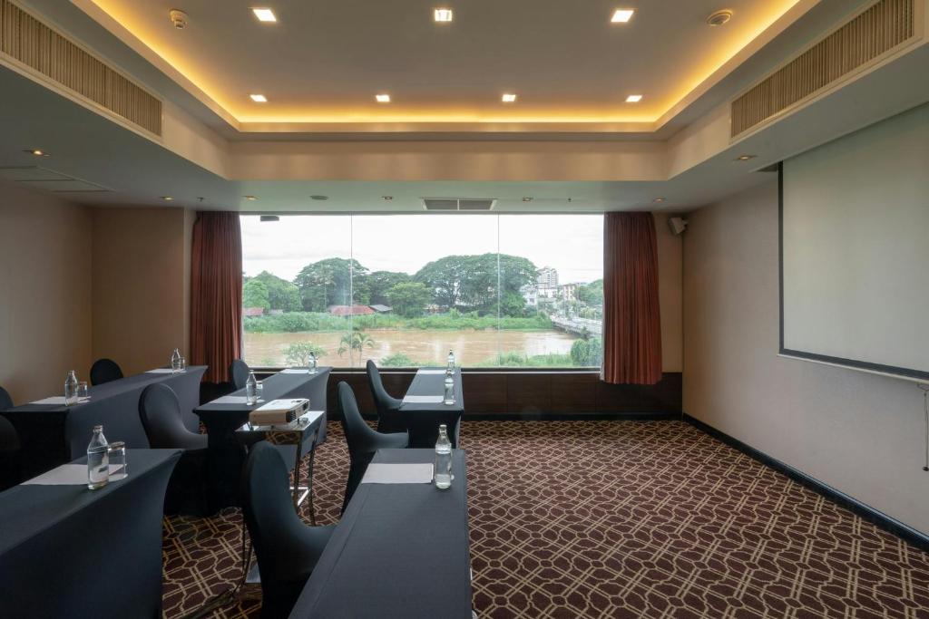 A meeting room with classroom seating, a projection screen and a broad green view.