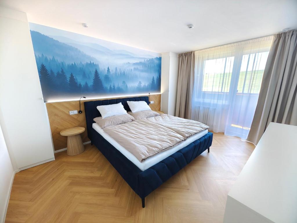 a bedroom with a bed with a painting on the wall at Base Camp - Apartmán Klínovec in Kovářská