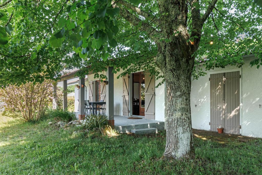 a white house with a tree in the yard at Villa L'Andélu - Conciergerieland in Saint-Michel-Escalus
