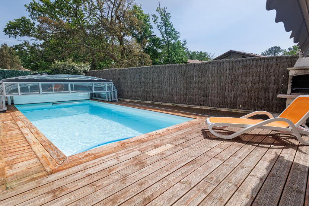 a swimming pool on a wooden deck with two chairs at Villa 4 Saisons, piscine chauffée in Vieux-Boucau-les-Bains