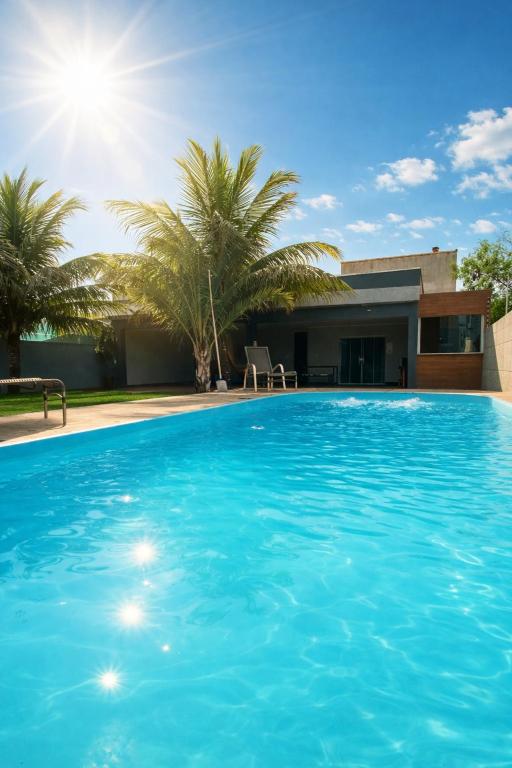 a swimming pool in front of a house with palm trees at Casa para temporada Diversão e sossego PRÓXIMA A PRAIA in Rio das Ostras