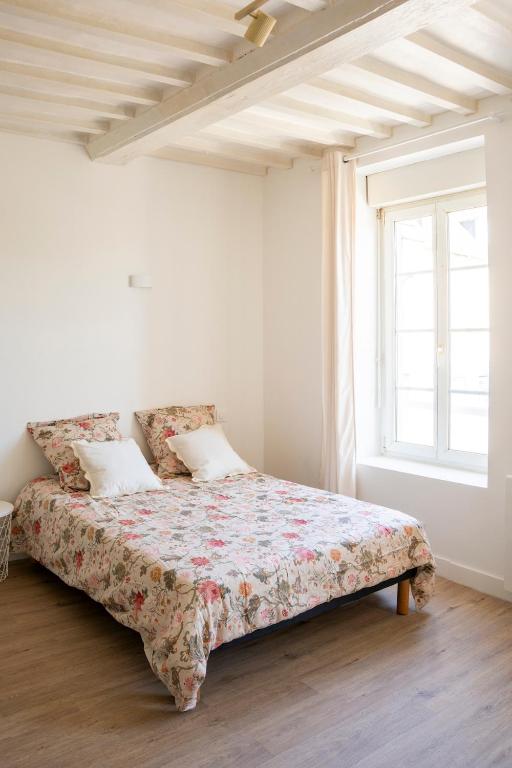 a bed in a white room with a window at Studio Saint-Patrice - centre historique Bayeux in Bayeux