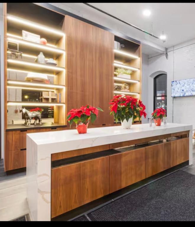 a kitchen with wooden cabinets and red flowers in vases at Historic Federal Hill 1Br Loft apt with onsite Gym and Barbershop in Providence