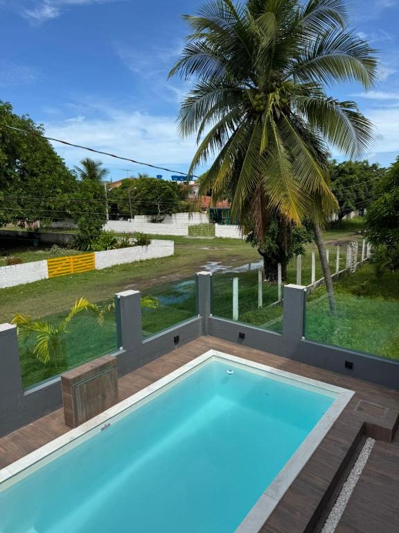 a swimming pool with a palm tree in the background at Pousada Pedra que Canta in Itamaracá