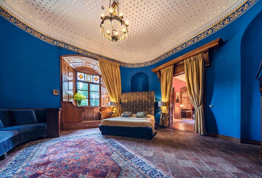 Curved blue bedroom with double bed, stained-glass window, gold curtains and patterned rug, intimate cozy feel