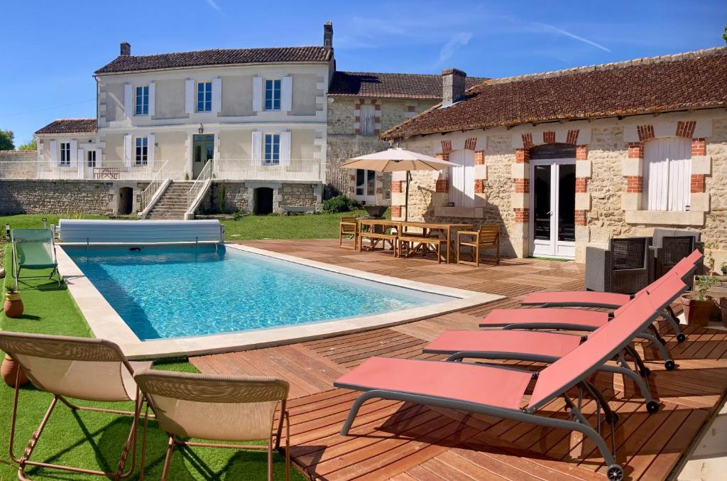 a backyard with a pool and chairs and a house at Le BRISSONNEAU in Saint-Saturnin