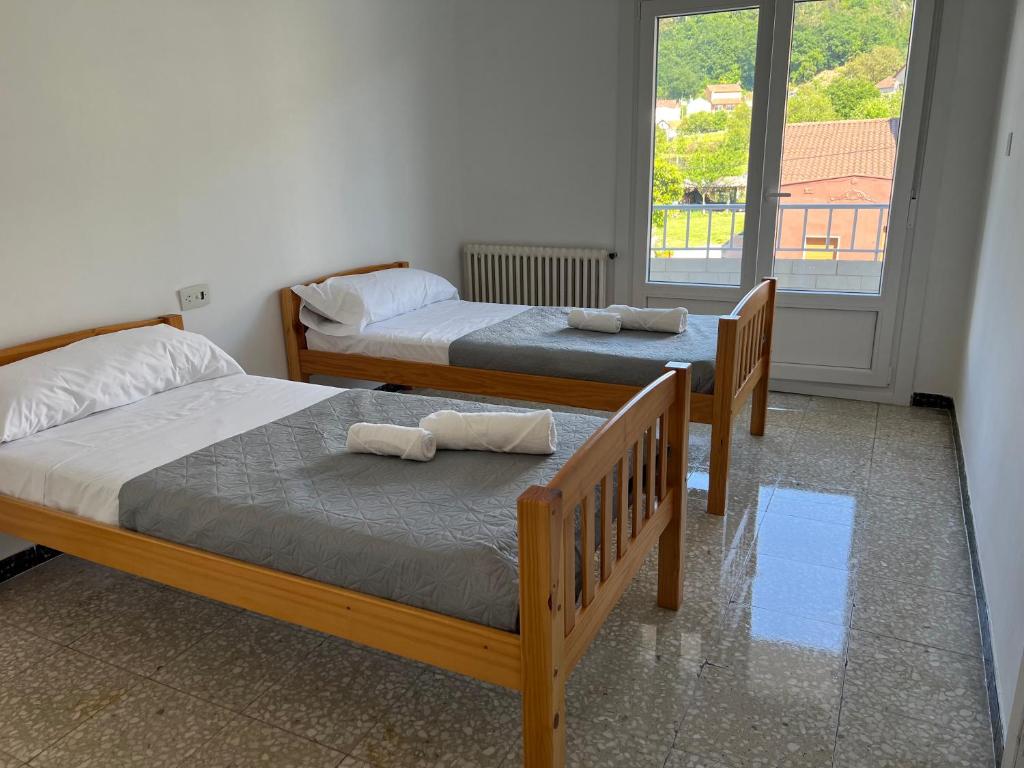two beds in a room with a window at pensión Palongo in Caldas de Reis