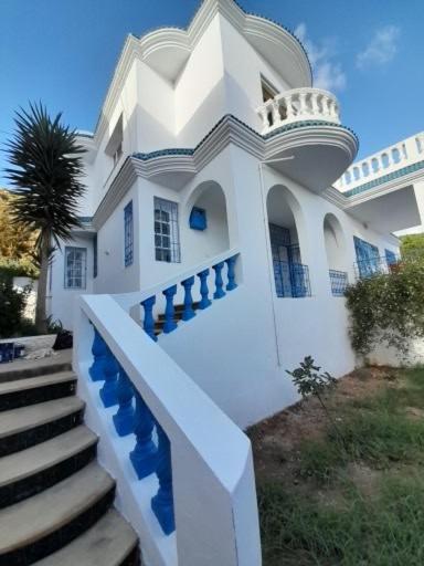 a white house with a staircase in front of it at Villa rafraf al hmeri in Rafrāf