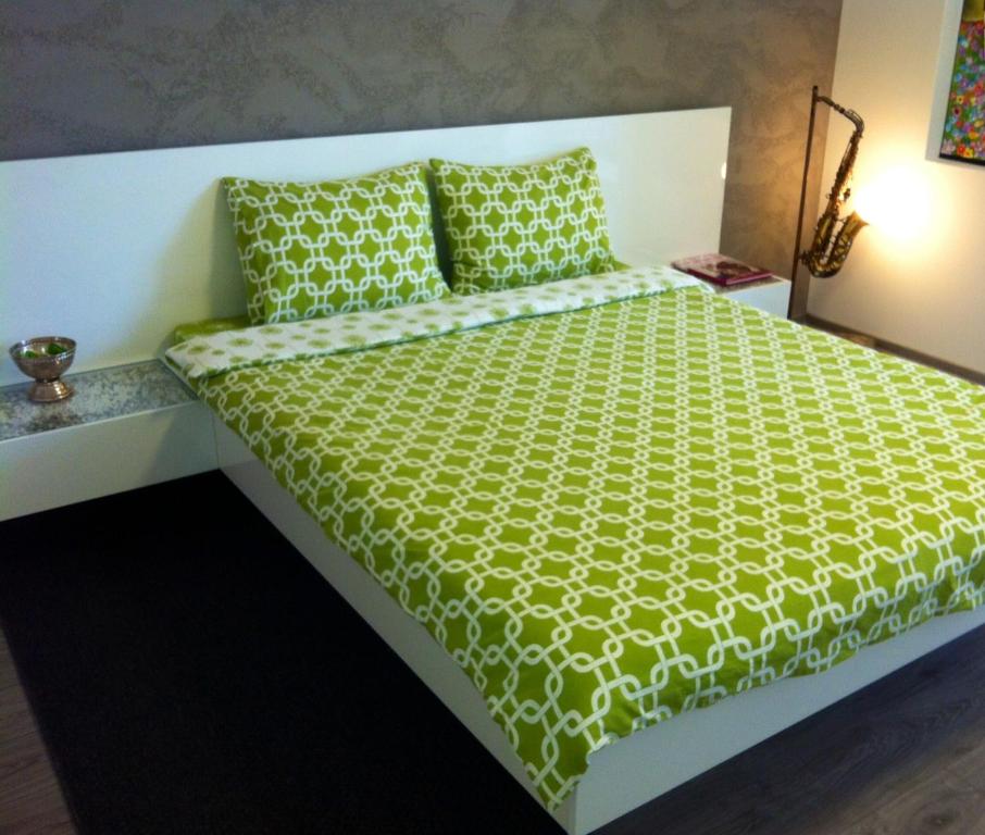 a bed with a green comforter and pillows at The Kiss Apartment in Timişoara