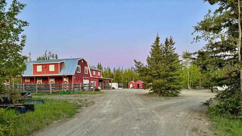a red barn with a blue roof on a dirt road at The Big Red Barn in Whitehorse