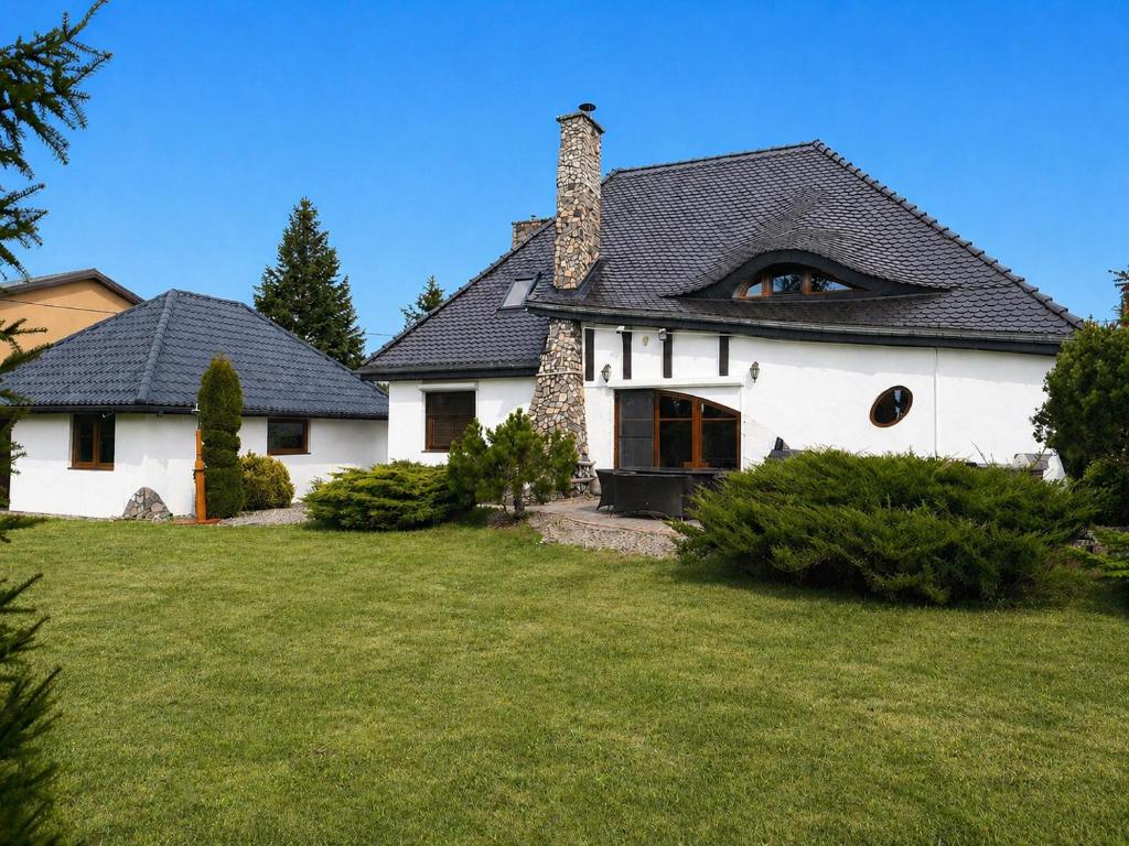 a white house with a black roof and a yard at Ostoja Tobołowo in Tobołowo