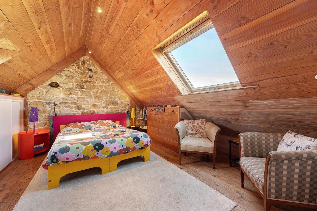 a bedroom with a bed and chairs in a attic at Chez Fred proche plage et gr34 in Plougoulm