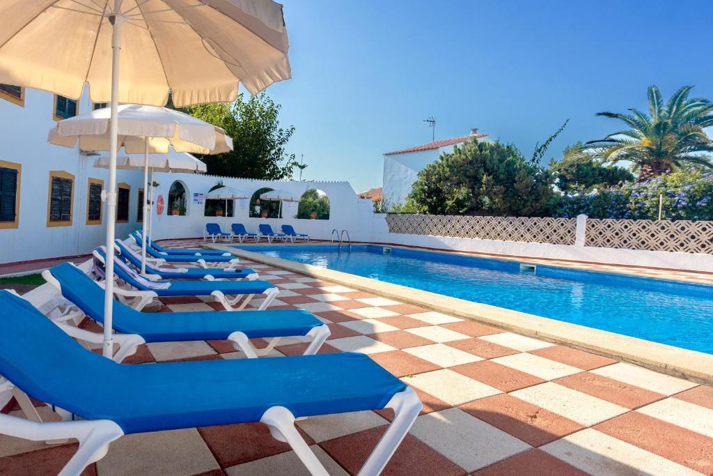 a pool with chairs and umbrellas next to a building at Bon repós B11 in Cala en Bosc