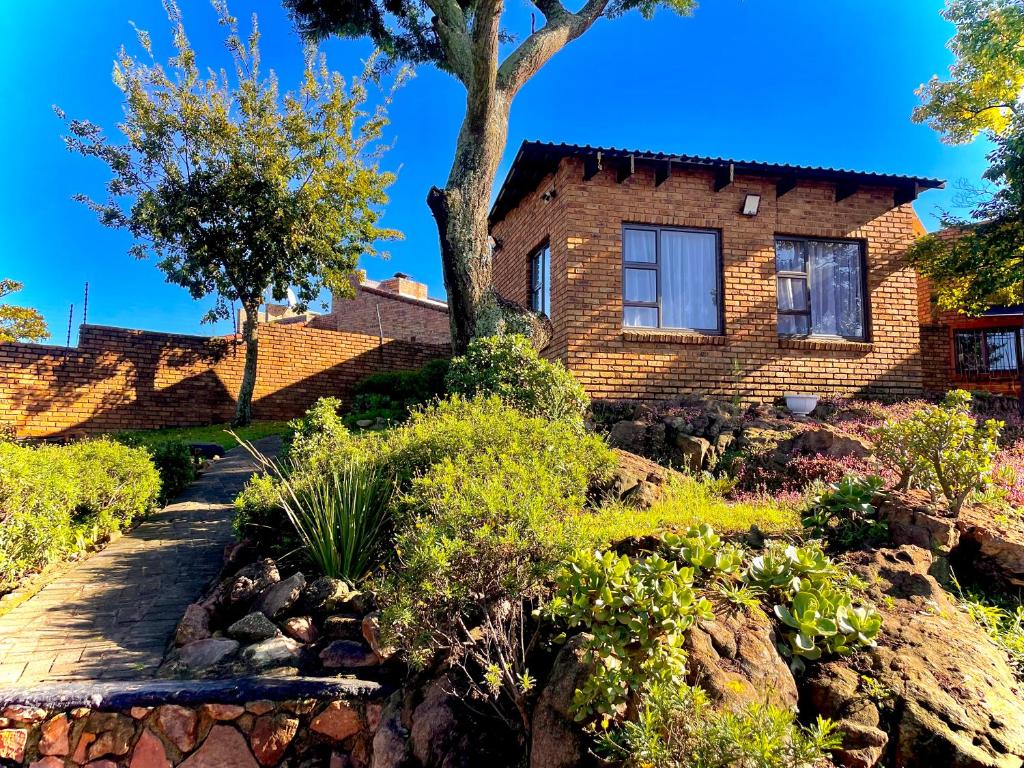 a brick house with a garden in front of it at Pinnacle Pearl View Cottage in Johannesburg