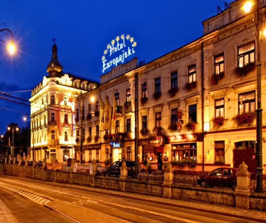 a building with a sign on top of it at night at Hotel Europejski in Krakow