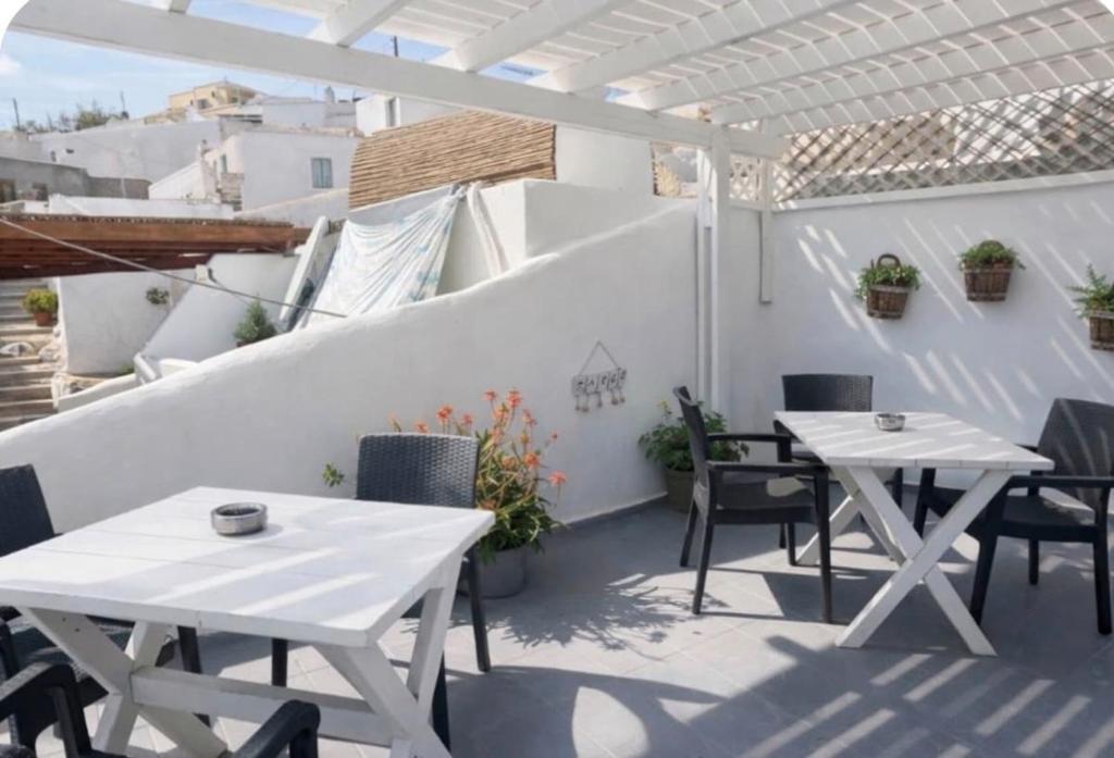 eine Terrasse mit weißen Tischen und Stühlen und einer weißen Wand in der Unterkunft Argo Studio! in Vóthon