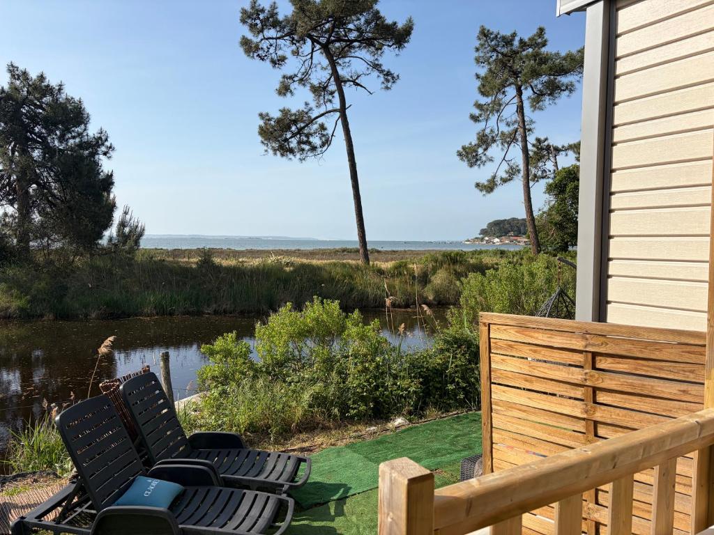 zwei Stühle auf einer Terrasse mit Blick auf einen Teich in der Unterkunft La Cabane in Claouey