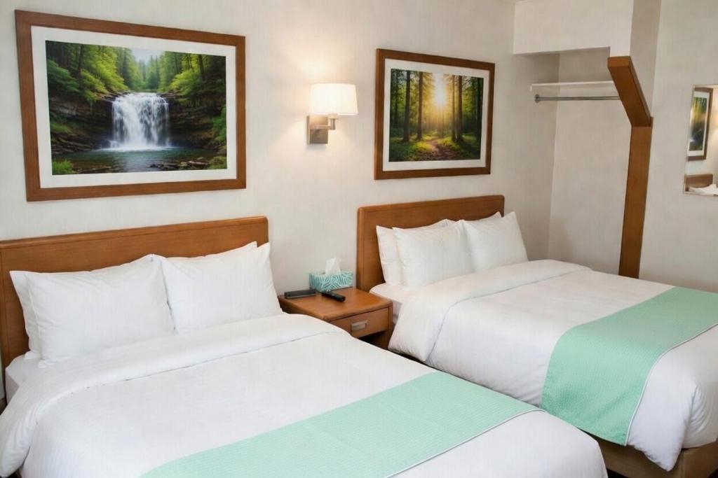 Zwei Betten in einem Hotelzimmer mit einem Wasserfallgemälde an der Wand in der Unterkunft Paddle Inn in Ely