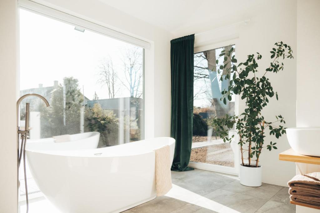 a bathroom with a white tub and a large window at AMRAI Magnetic in Ventspils