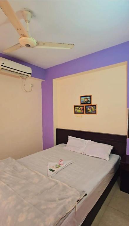 a bedroom with a bed with purple walls at Epindi Studio Apartment in Cox's Bazar